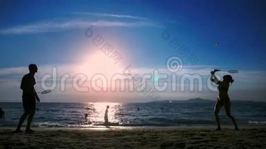 剪影。 人们在日落时在海滩上<strong>打羽毛球</strong>。